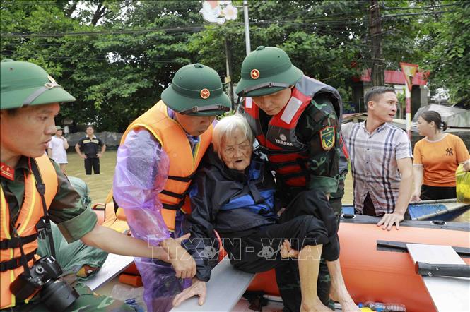 Cụ Nguyễn Thị Kỳ, 98 tuổi, ở xã Sơn Đông, huyện Lập Thạch, tỉnh Vĩnh Phúc được các chiến sĩ bộ đội giúp đỡ đưa lên thuyền cứu hộ đưa đến nơi an toàn. Ảnh: Hoàng Hùng - TTXVN