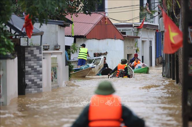 Lực lượng công an, dân quân tự vệ dùng thuyền di chuyển sâu vào trong thôn An Lạc, xã Trung Giã, huyện Sóc Sơn (Hà Nội) để cứu trợ và di chuyển người dân vùng ngập lụt tới nơi an toàn. Ảnh: Thanh Tùng - TTXVN