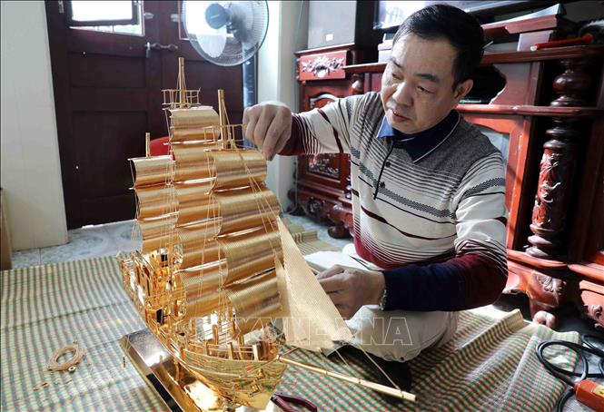 Hoàn thiện tác phẩm “Thuận buồm xuôi gió” của làng nghề chạm bạc Đồng Xâm. Ảnh: Thế Duyệt – TTXVN