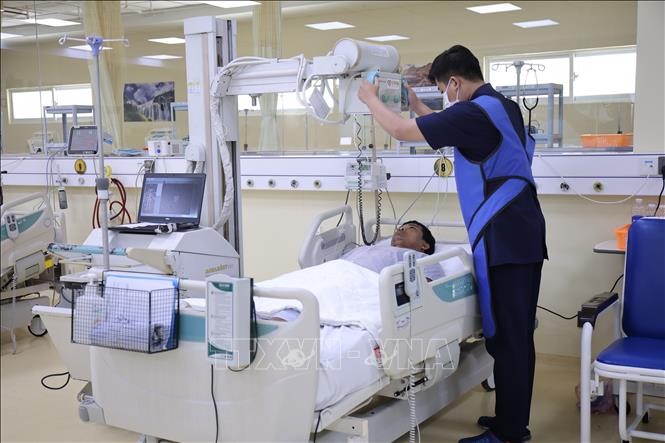 Kỹ thuật viên thao tác chụp X-quang tại giường kiểm tra cho bệnh nhân. Ảnh: Chanh Đa-TTXVN