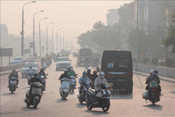 Người dân di chuyển trên đường trong điều kiện tầm nhìn bị hạn chế do ô nhiễm không khí, sáng 2/1/2024. Ảnh: Hoàng Hiếu - TTXVN