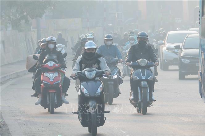 Người di chuyển ngoài đường nên đeo khẩu trang để phòng các bệnh hô hấp khi không khí hiện đang ô nhiễm nặng, sáng 2/1. Ảnh: Hoàng Hiếu - TTXVN