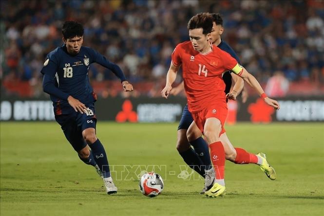 Đội trưởng Hoàng Đức (14) đi bóng qua sự truy cản của cầu thủ Thái Lan. Ảnh: Minh Quyết – PV TTXVN từ Thái Lan
