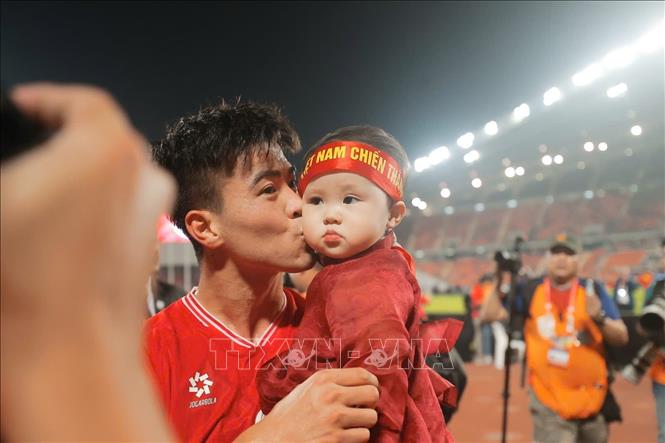 Duy Mạnh vui mừng ôm hôn cậu con trai được mẹ đưa đến sân xem bố thi đấu. Ảnh: Minh Quyết – PV TTXVN từ Thái Lan