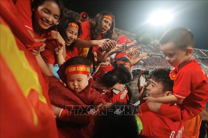 Duy Mạnh công kênh con trai trên cổ và chia sẻ niềm vui với người hâm mộ trên sân Rajamangala. Ảnh: Minh Quyết – PV TTXVN từ Thái Lan
