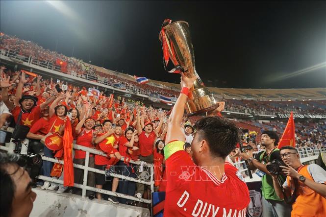 Duy Mạnh nâng cao cúp vô địch, chia vui cùng các cổ động viên Việt Nam trên sân Rajamangala. Ảnh: Minh Quyết – PV TTXVN từ Thái Lan
