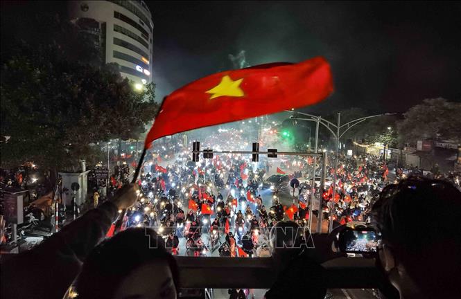 Người hâm mộ Thủ đô mang theo cờ Tổ quốc lên cầu vượt dành cho người đi bộ cổ vũ, ăn mừng chiến thắng. Ảnh: Thanh Tùng - TTXVN 