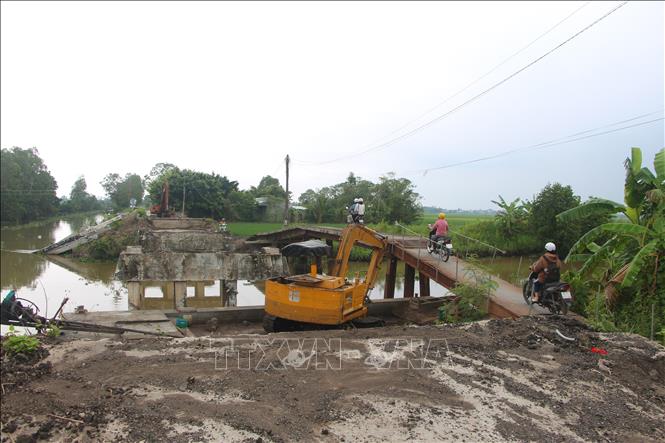 Do cầu chính chưa xong nên người dân phải lưu thông trên các cây cầu tạm. Ảnh: Chanh Đa - TTXVN