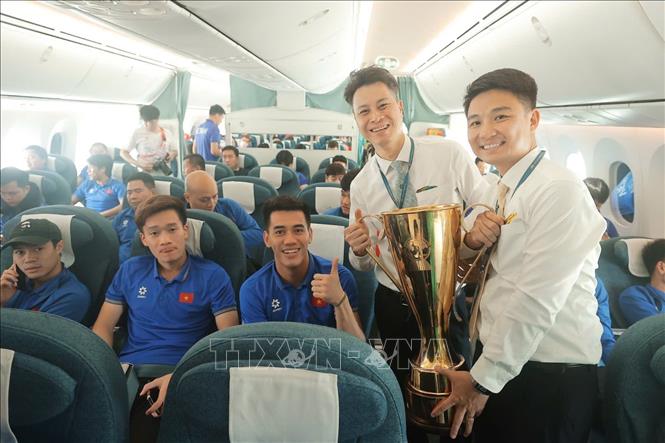 Thành viên tổ bay hân hoan được cầm cúp vô địch ASEAN Cup khi máy bay vừa hạ cánh. Ảnh: Minh Quyết - TTXVN