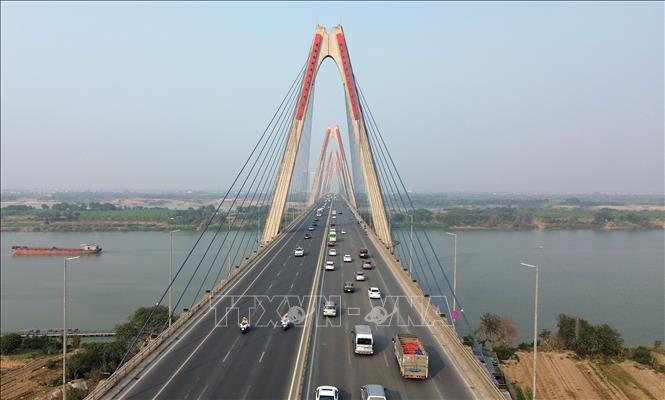 Xe dẫn đoàn và xe chở đội tuyển Việt Nam từ sân bay Nội Bài qua cầu Nhật Tân về trung tâm thành phố (trái). Ảnh: Quốc Khánh - TTXVN