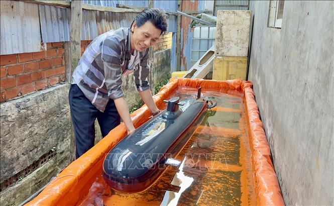 Anh Đệ thử nghiệm mô hình tàu ngầm trước khi giao cho khách hàng. Ảnh: Thanh Sang- TTXVN