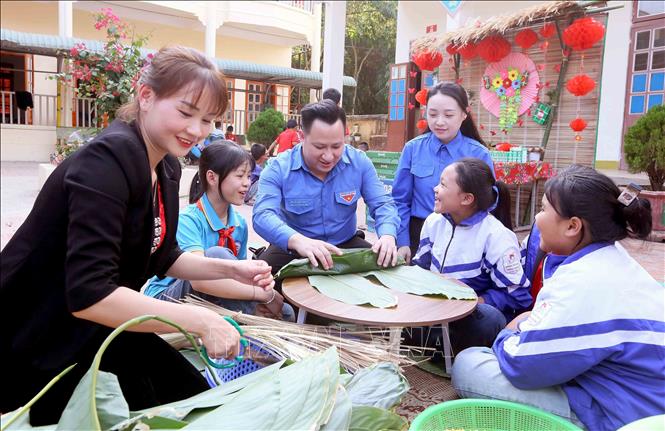 Hướng dẫn các em học sinh Trường Tiểu học Chiềng Ngàm, xã Chiềng Ngàm, huyện Thuận Châu, tỉnh Sơn La làm các loại bánh truyền thống trong dịp Tết Nguyên đán. Ảnh: Quang Quyết - TTXVN