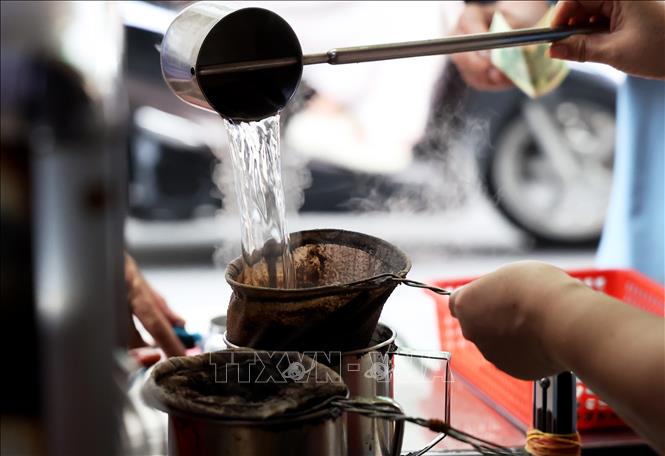 To make coffee, the barista spoons some ground coffee into the net, which is placed upon an empty stainless steel jug, then adds hot water, brews the coffee for a few seconds, then transfers to glasses to serve customers. VNA Photo: Hồng Đạt