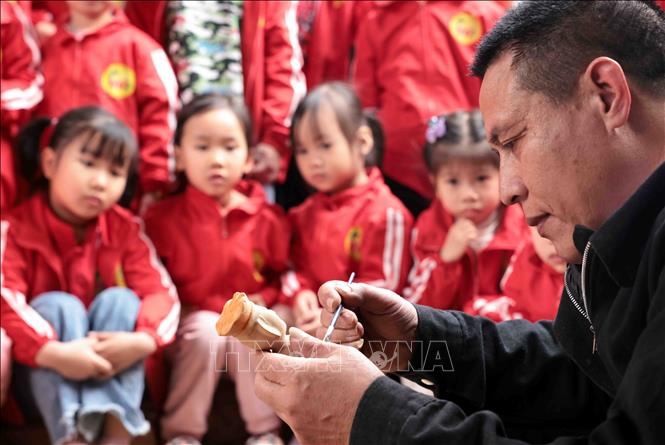 Nghệ nhân Nguyễn Văn Phi hướng dẫn cách sơn quân trò rối cho các khách du lịch 