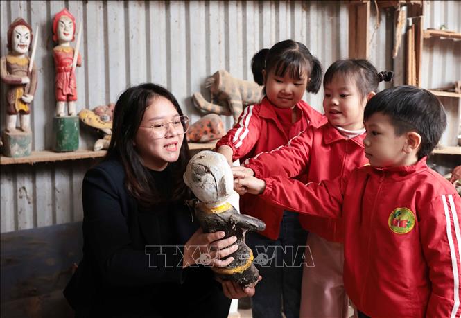 Trẻ nhỏ thích thú với những quân trò rối tại gia đình nghệ nhân Nguyễn Văn Phi khi được đến tham quan, trải nghiệm ở làng rối nước Đào Thục. Ảnh: Trần Việt - TTXVN