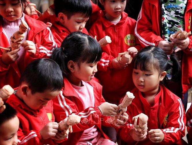 Trẻ nhỏ thích thú với những quân trò rối được chế tác tại gia đình nghệ nhân Nguyễn Văn Phi ở làng Đào Thục. Ảnh: Phạm Hậu - TTXVN