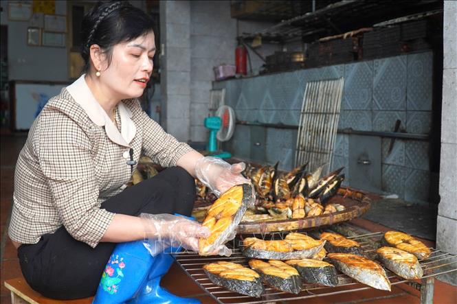 Chị Nguyễn Thị Thủy, chủ cơ sở cá nướng Quân Thủy tại thôn Nam Vượng, xã Ngư Lộc (Hậu Lộc, Thanh Hóa) kiểm tra chất lượng mẻ cá nướng. Ảnh: TTXVN phát