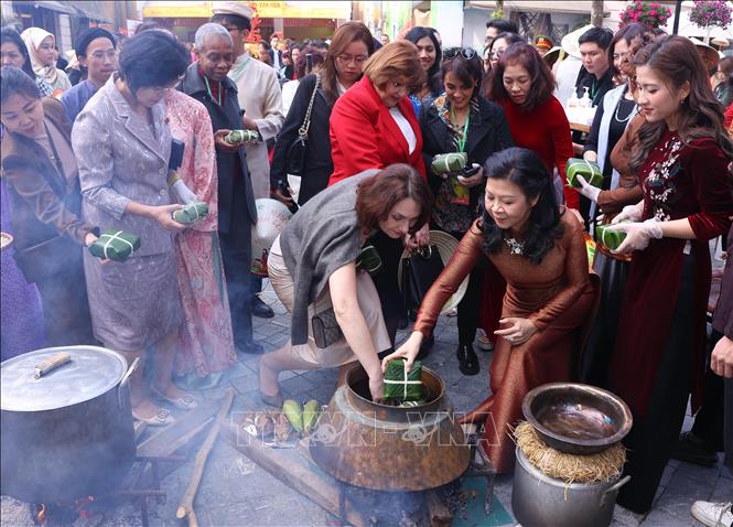 Bà Ngô Phương Ly, Phu nhân Tổng Bí thư Tô Lâm với các đại biểu trải nghiệm gói và luộc bánh chưng. Ảnh: Văn Điệp - TTXVN