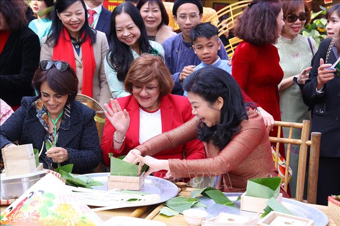 Bà Ngô Phương Ly, Phu nhân Tổng Bí thư Tô Lâm với các đại biểu trải nghiệm gói và luộc bánh chưng. Ảnh: Văn Điệp - TTXVN