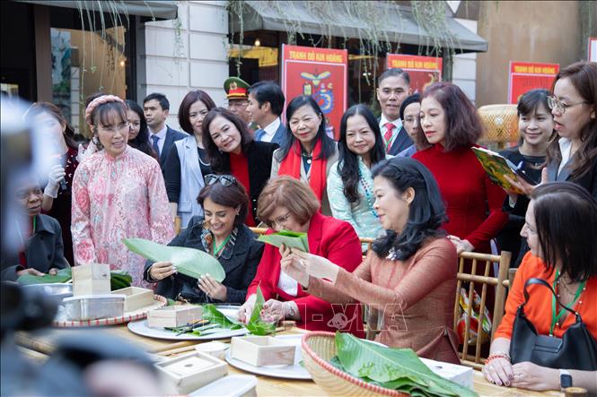 Bà Ngô Phương Ly, Phu nhân Tổng Bí thư Tô Lâm cùng các đại biểu trải nghiệm gói bánh chưng. Ảnh: Phương Thảo-TTXVN phát