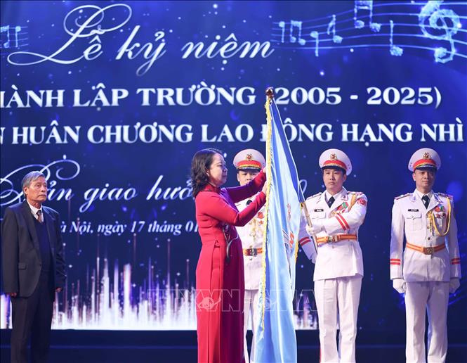 Phó Chủ tịch nước Võ Thị Ánh Xuân gắn Huân chương Lao động hạng Nhì lên cờ truyền thống của Trường THCS Đoàn Thị Điểm (quận Nam Từ Liêm, Hà Nội). Ảnh: Thanh Tùng - TTXVN