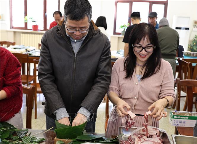 Đại sứ Phạm Thanh Bình cùng phu nhân tham gia gói bánh chưng. Ảnh: Quang Hưng - Phóng viên TTXVN tại Trung Quốc.