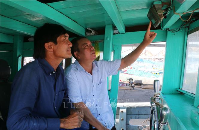 Checking monitoring devices installed in fishing boats docking at the Tran De port. VNA Photo: Tuấn Phi