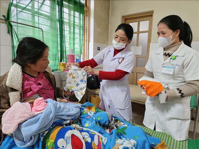 Điều dưỡng Trung tâm Y tế huyện A Lưới tặng áo quần sơ sinh mới cho sản phụ đến từ huyện Kà Lừm, tỉnh Sê Kông, Lào. Ảnh: Mai Trang - TTXVN
