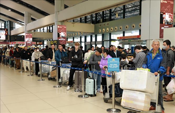 Người dân, du khách xếp hàng chờ làm thủ tục check-in tại sân bay quốc tế Nội Bài, sáng 25 tháng Chạp. Ảnh: Quốc Khánh - TTXVN