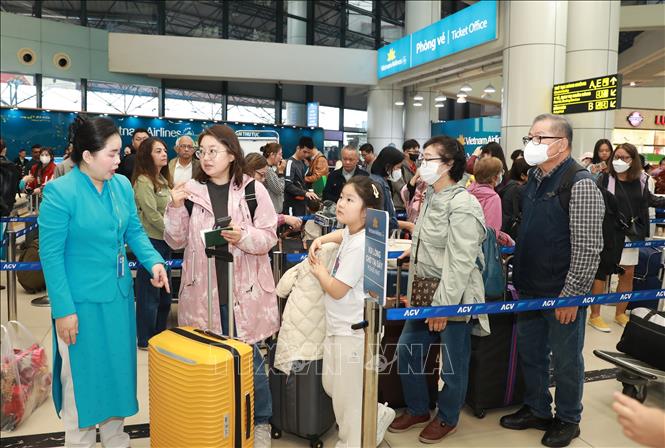 Hướng dẫn viên của Vietnam Airlines hướng dẫn người dân, du khách xếp hàng lần lượt vào làm thủ tục. Ảnh: Quốc Khánh - TTXVN