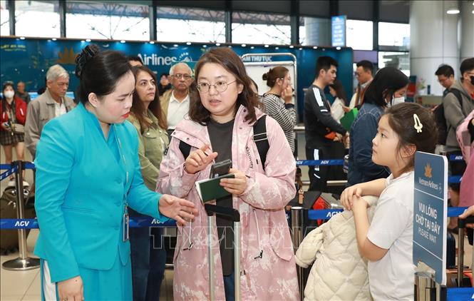 Hướng dẫn viên của Vietnam Airlines hướng dẫn người dân, du khách làm thủ tục check-in vé điện tử. Ảnh: Quốc Khánh - TTXVN