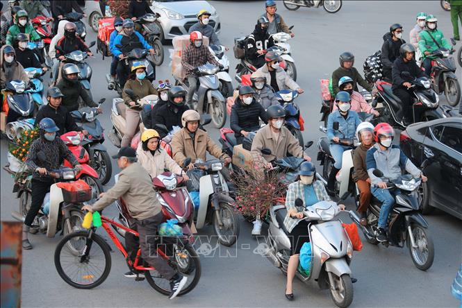 Nhiều người dân với hành lý, hoa đào... di chuyển từ hướng nội thành Hà Nội đi các tỉnh phía Nam từ đường Ngọc Hồi. Ảnh: Hoàng Hiếu - TTXVN