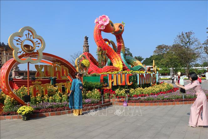 Người dân chụp ảnh cùng linh vật rắn Tết Ất Tỵ 2025 tại khu vực Đài tưởng niệm chiến sĩ trận vong (hay còn gọi là Bia Quốc Học). Ảnh: Mai Trang - TTXVN