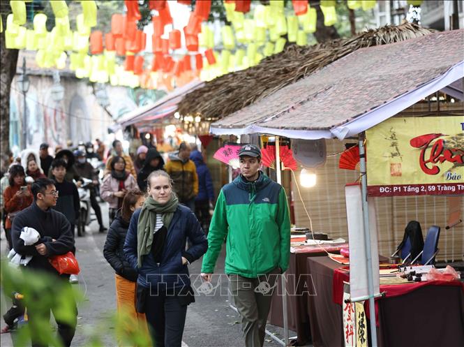 Du khách nước ngoài khám phá bích họa phố Phùng Hưng. Ảnh: Thanh Tùng - TTXVN