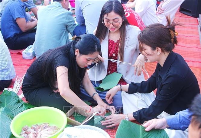 Các cô gái người Campuchia hào hứng trổ tài gói bánh chưng. Ảnh: Quang Anh – PV TTXVN tại Campuchia