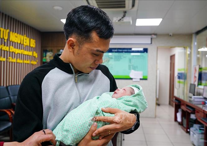 Anh Nguyễn Văn Hùng xúc động nghẹn ngào khi được bế trên tay đứa con vừa chào đời. Ảnh: Khánh Hoà - TTXVN