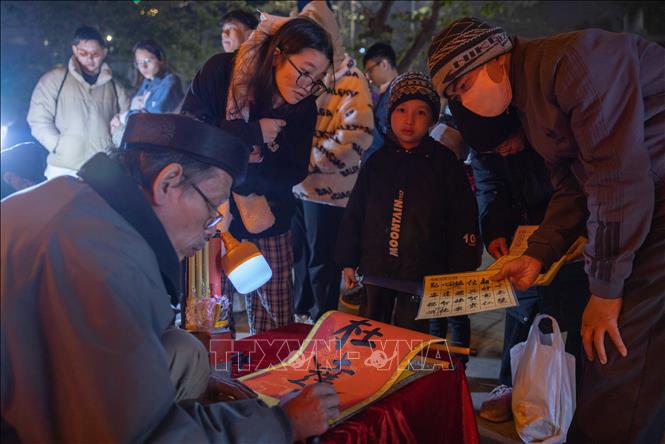 Người dân xin chữ tại khu vực đền Bà Kiệu trong thời khắc đầu tiên của năm mới Ất Tỵ. Ảnh: Hoàng Hiếu - TTXVN