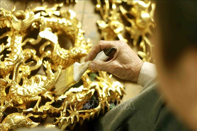 Thếp vàng sản phẩm đồ thờ tại làng nghề mộc Bích Chu. Ảnh: Hoàng Hùng - TTXVN