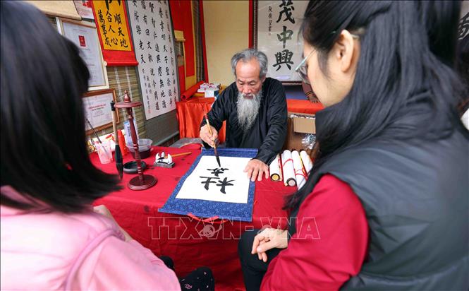 Xin chữ đầu năm tại khu di tích Văn Miếu - Quốc Tử Giám với ước vọng con cái học hành, thi cử đỗ đạt và gặp nhiều may mắn cũng là nét đẹp truyền thống của người dân Thủ đô mỗi dịp du Xuân. Ảnh: Phạm Kiên - TTXVN