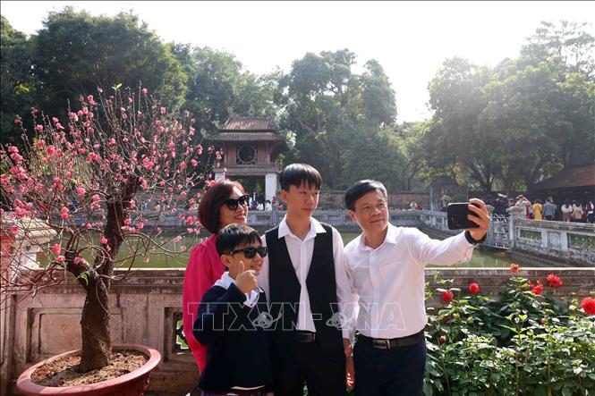 Một gia đình lưu giữ lại hình ảnh tại khu di tích Văn Miếu - Quốc Tử Giám trong tiết trời ấm áp mùng 3 Tết Nguyên đán Ất Tỵ 2025. Ảnh: Phạm Kiên - TTXVN