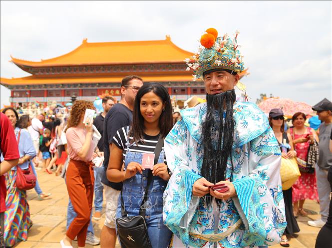 Du khách thích thú chụp ảnh lưu niệm cùng nhân vật Thần Tài trong dân gian của người châu Á. Ảnh: Hồng Minh - p/v TTXVN tại Pretoria, Nam Phi