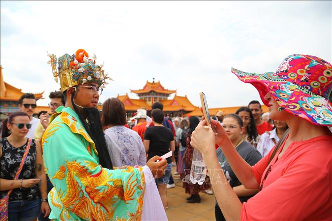 Du khách thích thú chụp ảnh lưu niệm cùng nhân vật Thần Tài trong dân gian của người châu Á. Ảnh: Hồng Minh - p/v TTXVN tại Pretoria, Nam Phi
