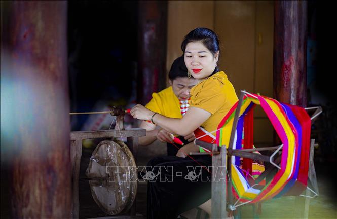 Phụ nữ dân tộc Thái kéo sợi để dệt khăn Piêu. Ảnh: Xuân Tư – TTXVN
