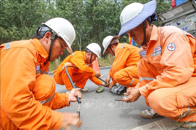 Những thành viên dưới mặt đất chuẩn bị các thiết bị thay thế để chuyển lên lưới điện lắp rắp. Ảnh: Giang Phương - TTXVN