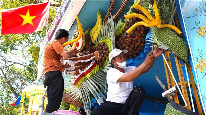 Người theo đạo Cao Đài thực hiện mô hình rồng bằng củ, quả trưng bày trước ngày diễn ra Đại Lễ Đức Chí Tôn năm Ất Tỵ. Ảnh: Minh Phú - TTXVN