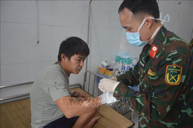 Kiểm tra, băng bó vết thương ở bàn tay cho ngư dân. Ảnh: TTXVN phát
