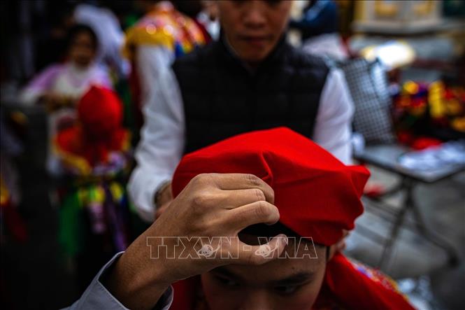 Giữ khăn để tạo ra hình dáng đặc trưng giống mỏ quạ trước khi thắt múi ở gáy, thường được sử dụng trong các trang phục truyền thống hoặc trong những dịp lễ hội đặc biệt. Ảnh: Phạm Tuấn Anh - TTXVN