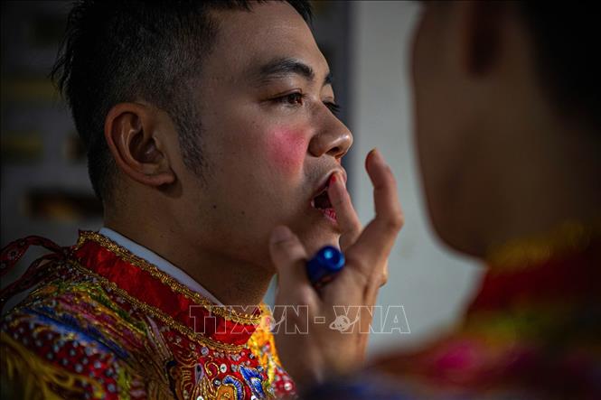 Thành viên CLB trống bồng Triều Khúc đánh má phấn, tô son... hoá trang giả gái chuẩn bị cho biểu diễn múa bồng. Ảnh: Phạm Tuấn Anh - TTXVN 