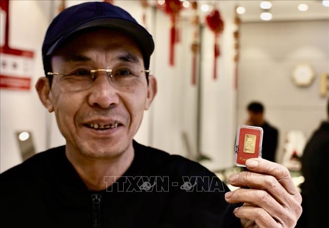 Một người dân vui vẻ sau khi mua vàng tại Công ty Phú Quý. Ảnh: Trần Việt - TTXVN 