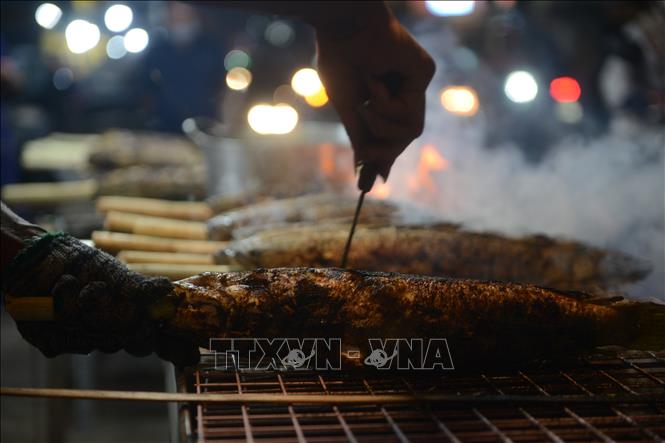 Để có một con cá lóc nướng vàng ươm, người nướng phải khéo léo, trở tay đều để cá không bị cháy. Ảnh: Mạnh Linh - TTXVN